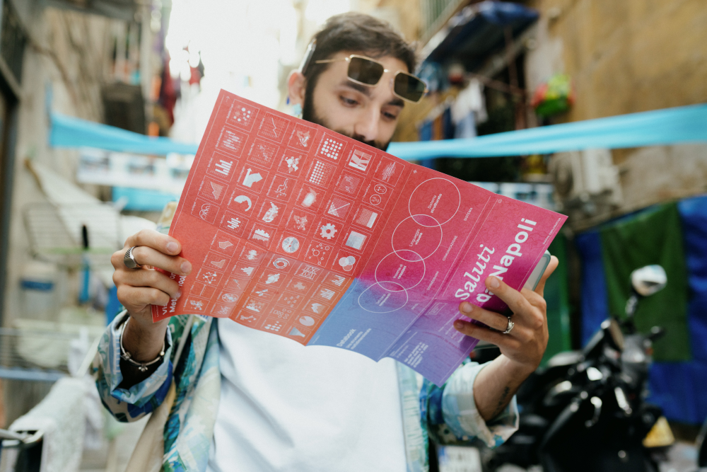 A man looking at the "Greetings from ... Naples" map